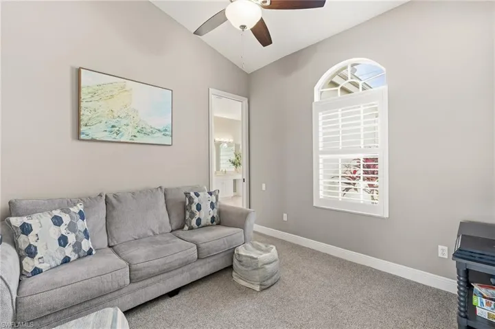 Carpeted living room with ceiling fan, lofted ceiling, and plenty of natural light