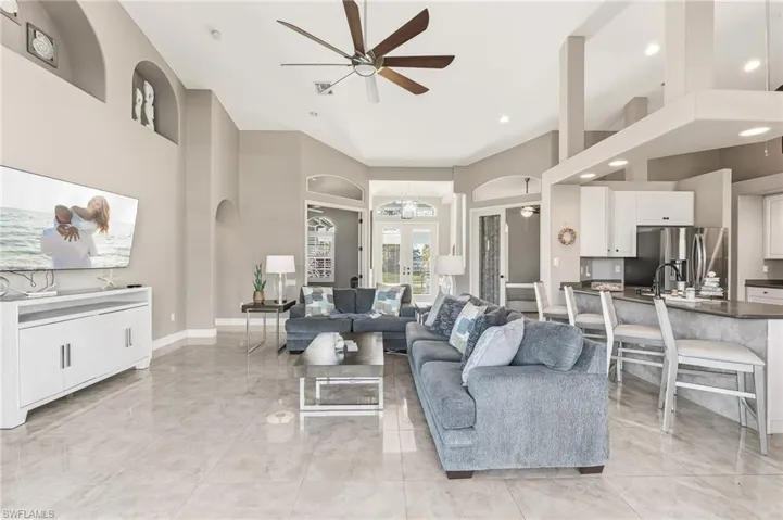 Living area with ceiling fan, arched walkways, a towering ceiling, and recessed lighting