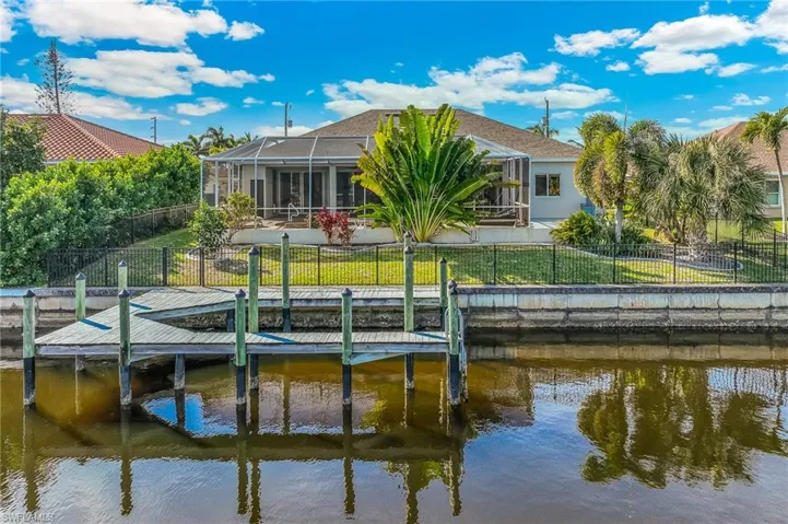 Back of house with a fenced backyard, glass enclosure, a water view, and a sunroom
