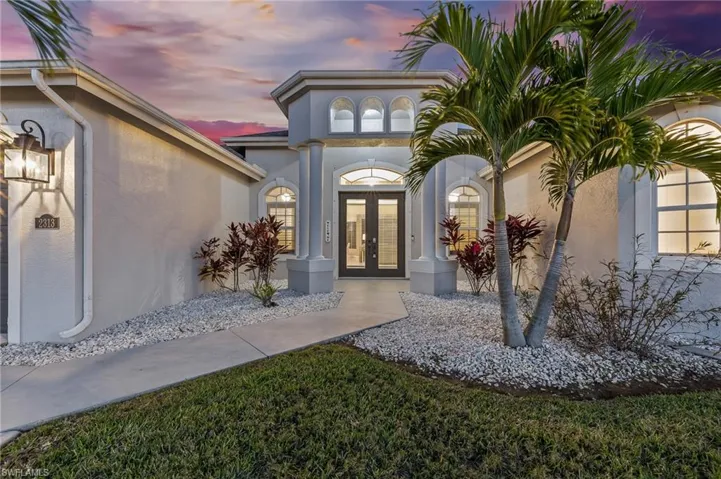 Exterior entry at dusk featuring french doors and stucco siding