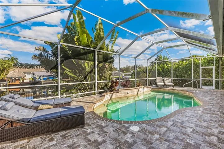 Outdoor pool featuring glass enclosure, a sunroom, and a patio