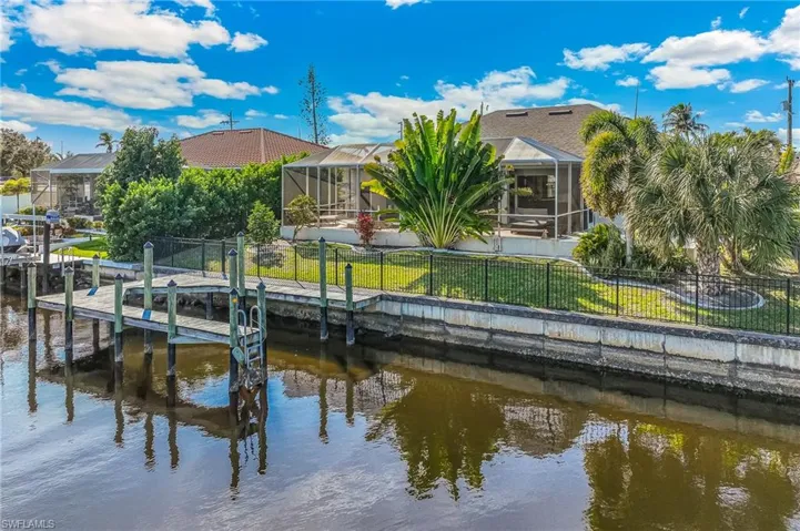 Back of property featuring a fenced backyard, a sunroom, glass enclosure, and a water view