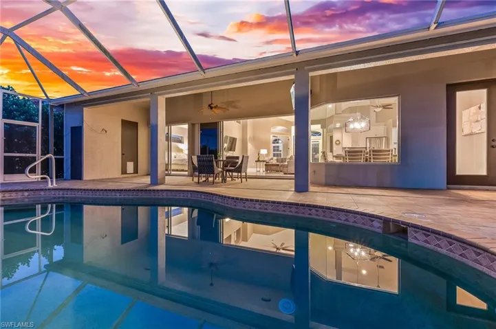 Outdoor pool featuring glass enclosure, outdoor dining area, a sunroom, and a patio