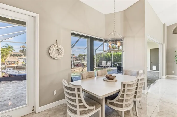 Dining space featuring a sunroom, high vaulted ceiling, and a chandelier