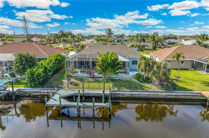 Back of house with a lanai, boat lift, a sunroom, and a water view