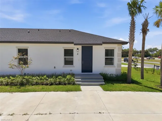 Contemporary stucco exterior with a dark shingle roof and contrasting dark entry door