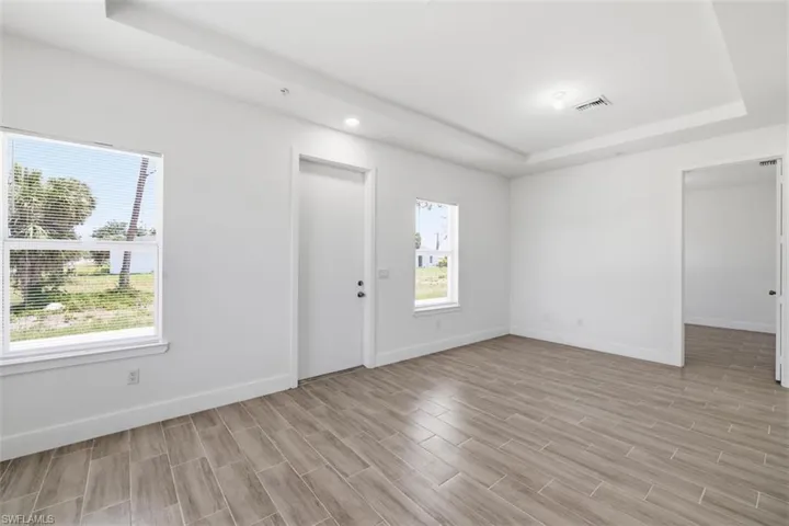 Spacious room featuring wood-finish tile flooring and a tray ceiling with recessed lighting