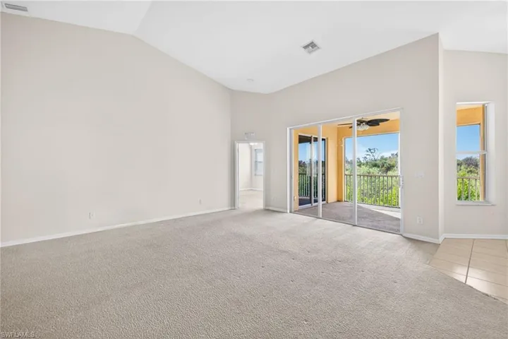Carpeted spare room featuring vaulted ceiling and baseboards