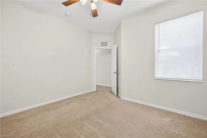 Carpeted spare room featuring ceiling fan and baseboards