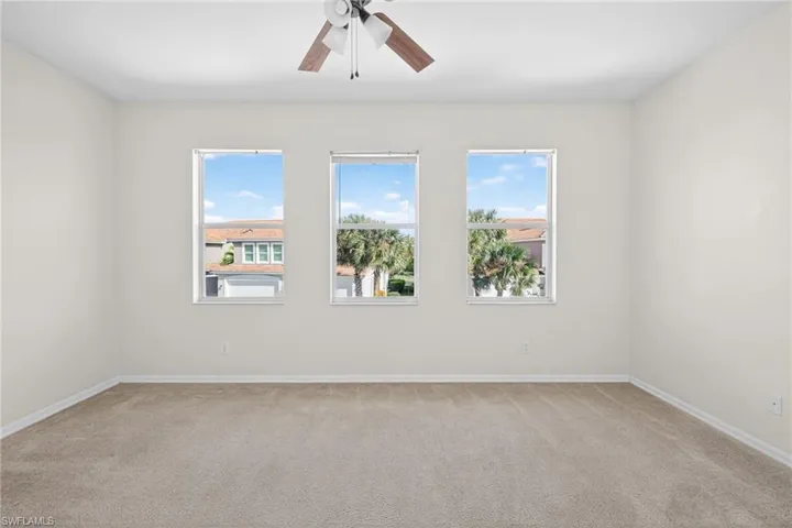 Unfurnished room featuring plenty of natural light, light carpet, and a ceiling fan
