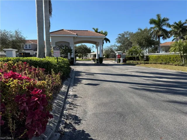 View of asphalt road featuring curbs and a gated entry
