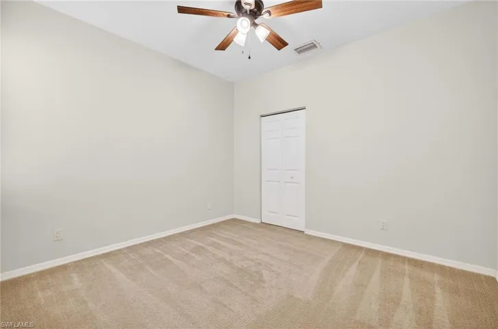 Spare room featuring light carpet and ceiling fan