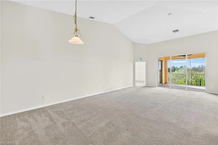 Unfurnished room featuring carpet and high vaulted ceiling