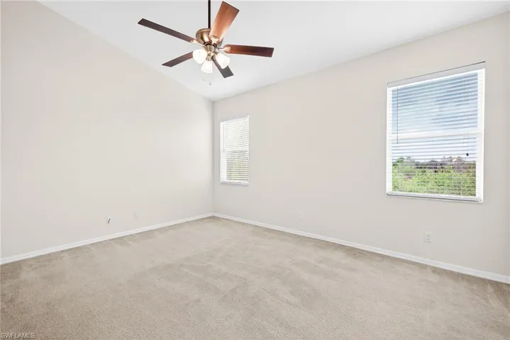 Unfurnished room featuring light colored carpet, vaulted ceiling, and ceiling fan