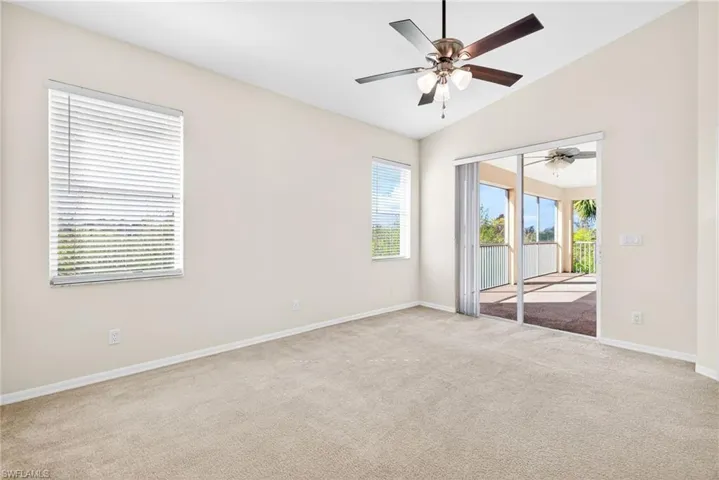 Empty room with lofted ceiling, light carpet, and a ceiling fan