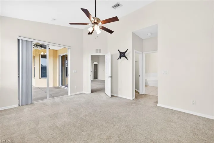 Unfurnished bedroom with light carpet, ceiling fan, and ensuite bathroom