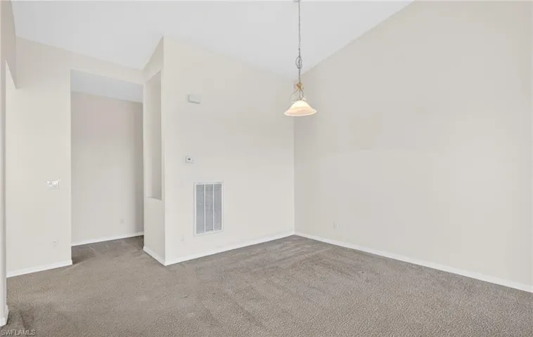 Carpeted spare room with lofted ceiling and baseboards