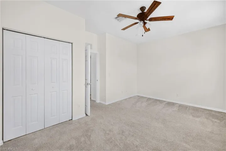 Unfurnished bedroom featuring light carpet, ceiling fan, and a closet