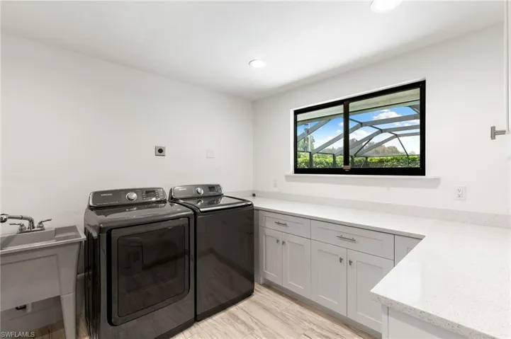 Washroom with sink, cabinets, washer and dryer, and light wood-type flooring