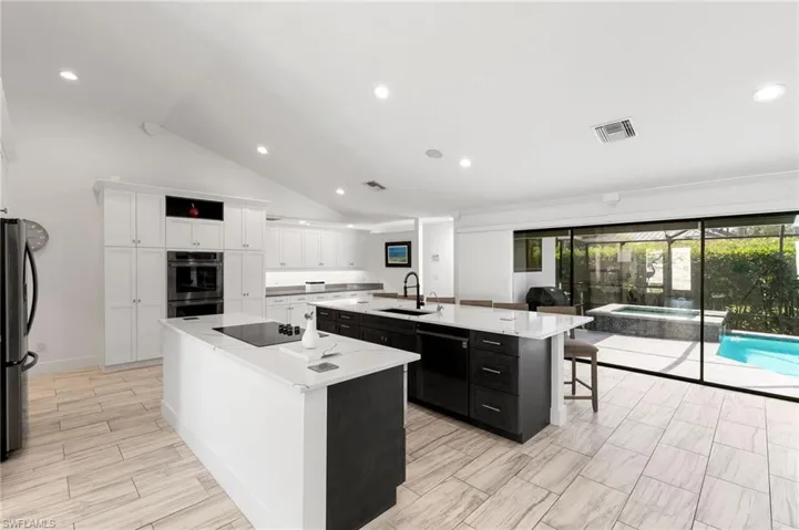 Kitchen featuring black appliances, white cabinets, sink, a kitchen island with sink, and a kitchen breakfast bar