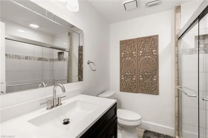 Bathroom featuring toilet, vanity, and an enclosed shower