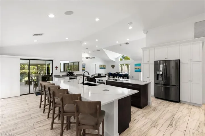 Kitchen with stainless steel fridge with ice dispenser, white cabinetry, ceiling fan, a spacious island, and high vaulted ceiling