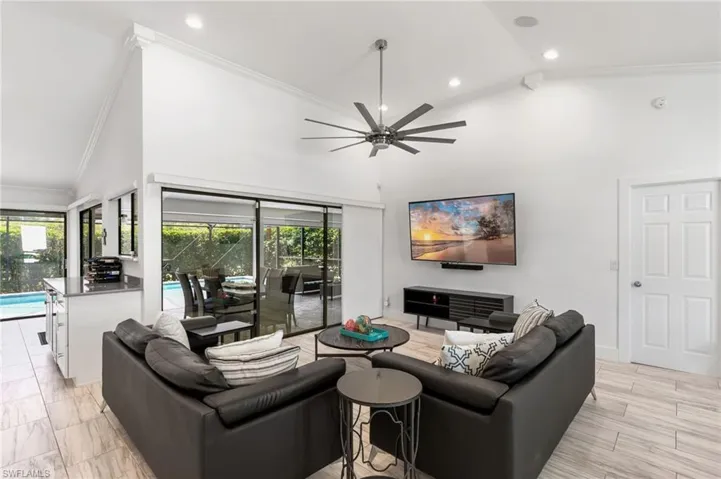 Living room featuring ornamental molding, a healthy amount of sunlight, ceiling fan, and high vaulted ceiling
