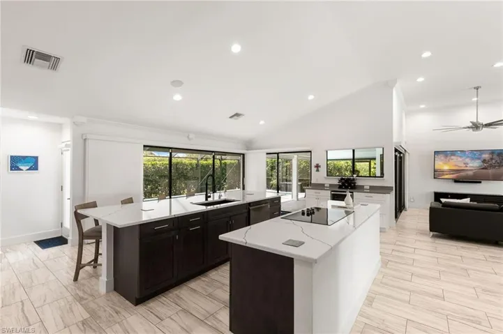 Kitchen featuring light stone countertops, sink, a kitchen island, and ceiling fan