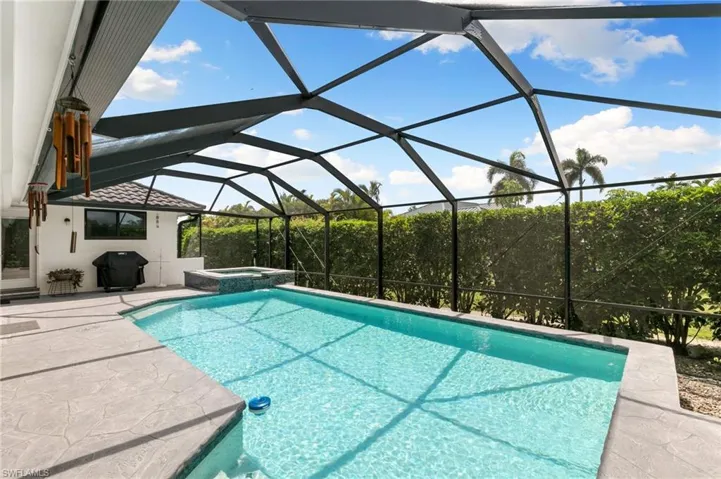 View of pool with an in ground hot tub, a patio area, glass enclosure, and a grill