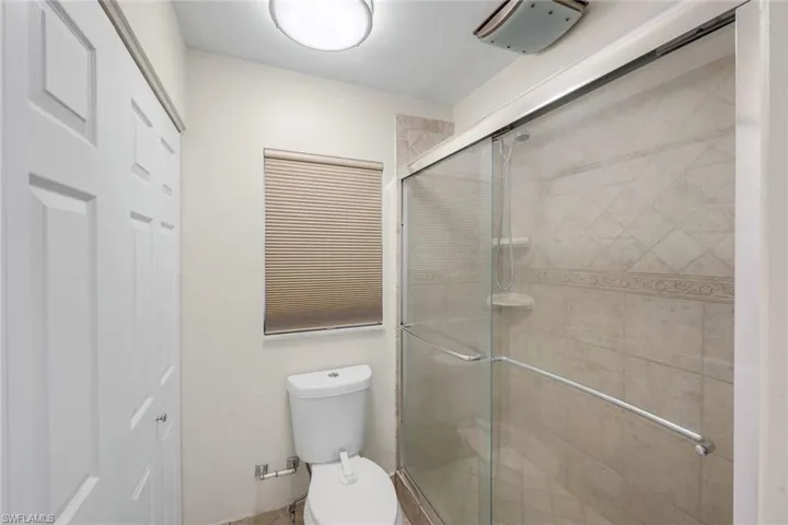 Glass-enclosed shower with tiled walls featuring decorative inlay