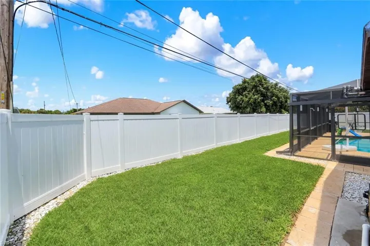 Expansive backyard featuring a manicured lawn and a white privacy fence