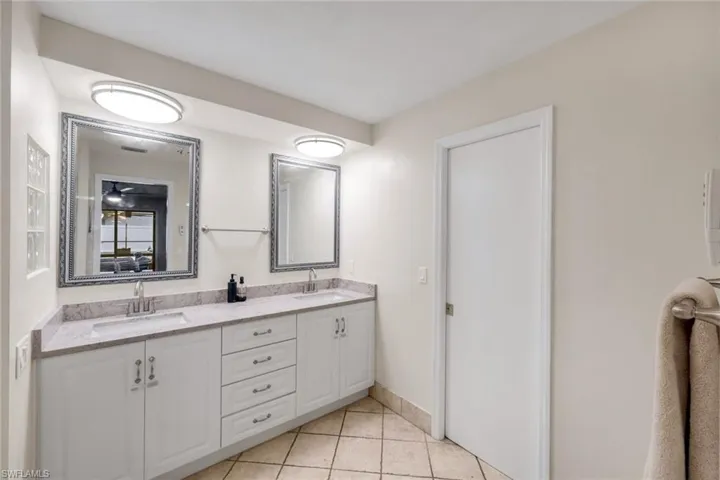 White double vanity featuring dual integrated sinks, chrome faucets, and a speckled countertop