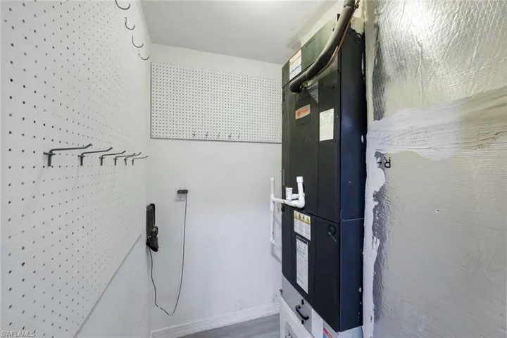 Utility area featuring a large HVAC system, white pegboard wall panels, and gray flooring