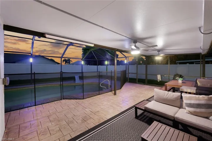 Covered patio area featuring a textured paver deck, ceiling fans, and overhead lighting