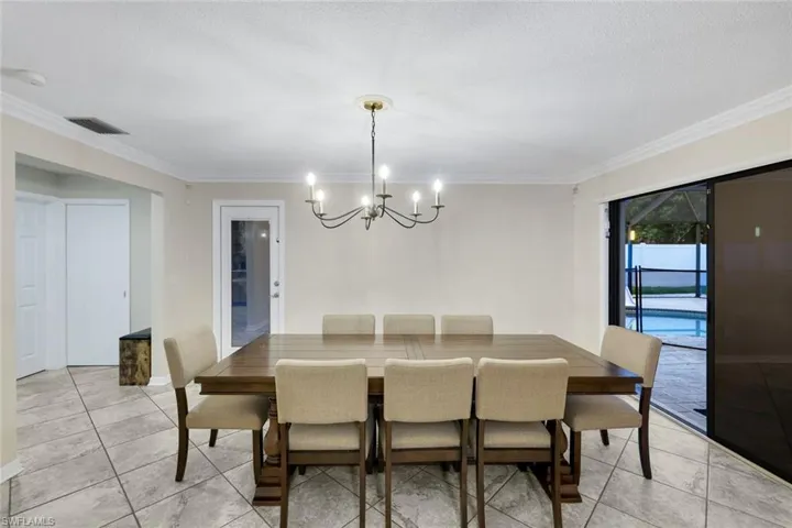 Spacious dining area featuring a chandelier, crown molding, and tiled flooring