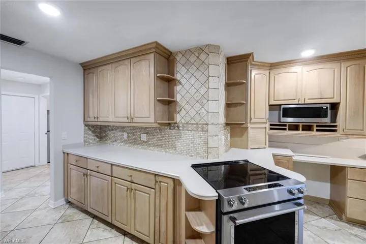 Kitchen featuring light wood cabinetry, light countertops, and a mosaic tile backsplash