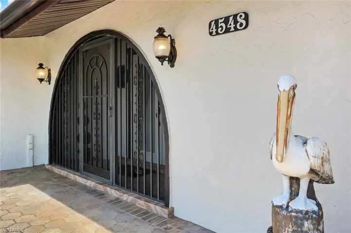 Arched entryway featuring an ornate iron security gate and paver flooring