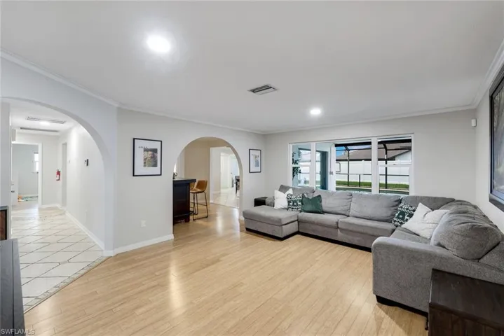 Spacious living area featuring wood-finish flooring, recessed lighting, and crown molding
