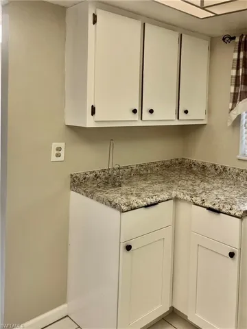 Kitchen with white cabinetry, light stone countertops, and light tile patterned floors