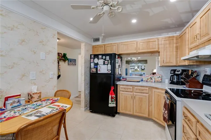 Kitchen with white  ornamental molding, light brown cabinetry, and light countertops