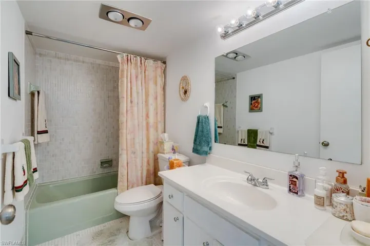 Bathroom with vanity, shower / bathtub combination with curtain, and light tile patterned flooring