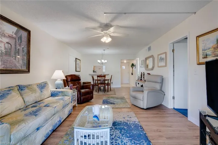 Living room featuring light wood finished floors, and a ceiling fan chandelier