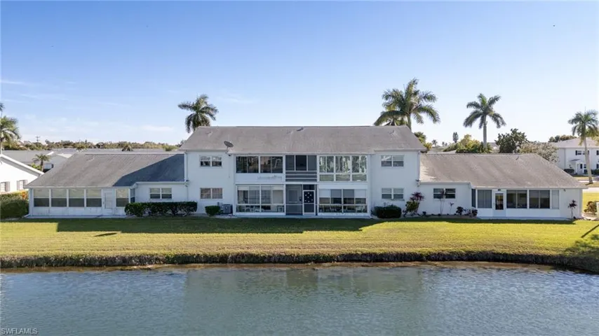Back of house featuring a sunroom, a water view, and a yard