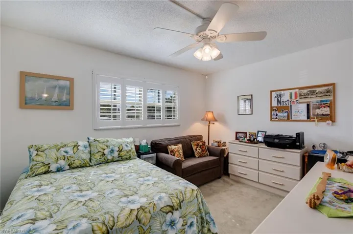 Bedroom with a textured ceiling, a ceiling fan, and light colored carpet