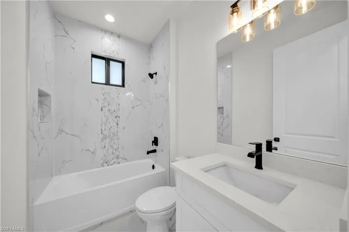 Full bathroom with toilet, vanity, and washtub / shower combination