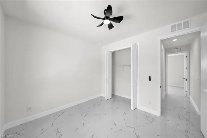 Unfurnished bedroom with a closet, visible vents, baseboards, marble finish floor, and a ceiling fan