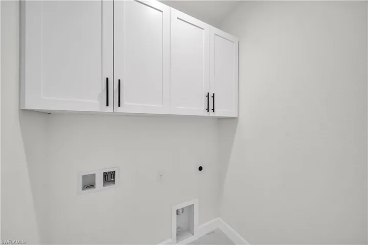 Clothes washing area featuring hookup for an electric dryer, baseboards, marble finish floor, cabinet space, and washer hookup