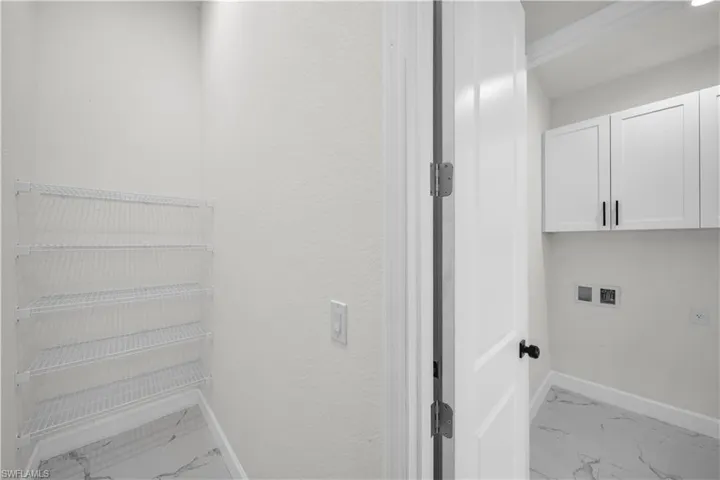 Washroom with marble finish floor, baseboards, washer hookup, and cabinet space