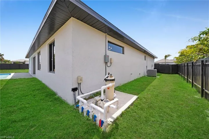 Rear view of property with stucco siding, cooling unit, a yard, and a fenced backyard