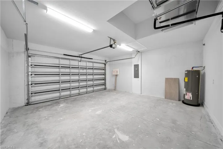 Garage featuring water heater, electric panel, and a garage door opener